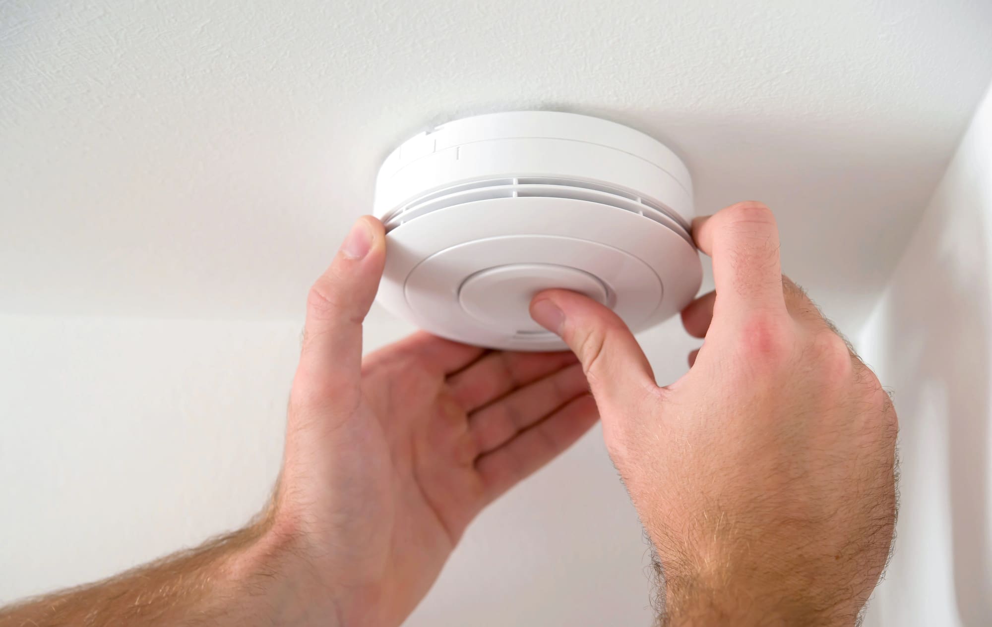 Smoke detector replacement services performed by technician installing new ceiling device